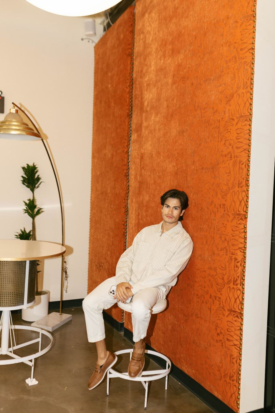 Jose seated against the orange wall at the studio