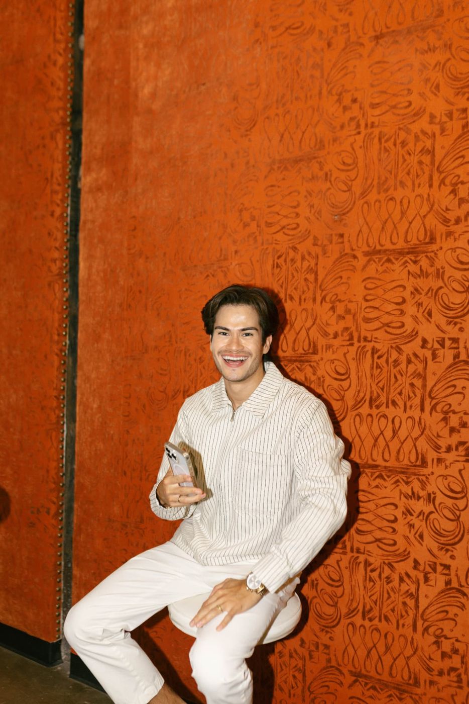 Jose laughing against an orange patterned wall